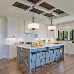 a large kitchen with an island in the middle and three stools at the end