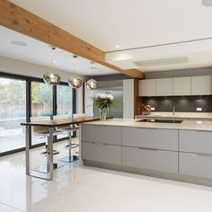 a modern kitchen with stainless steel appliances and marble counter tops, along with large windows