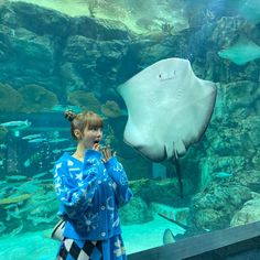 a woman standing in front of a large fish tank