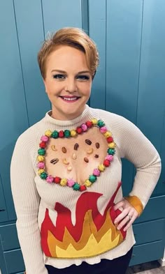 a woman is standing in front of a blue door wearing a sweater with pom poms on it