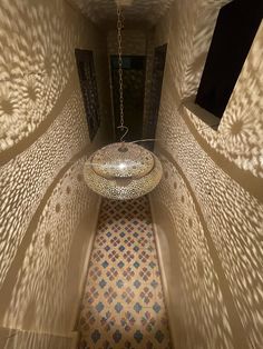 the light is shining on the floor and ceiling in this hallway with an intricately designed lamp