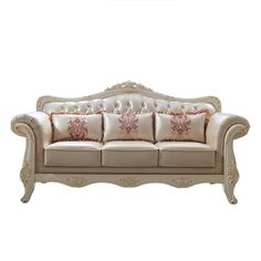 a white couch with pink and gold pillows on it's back end, sitting in front of a white wall