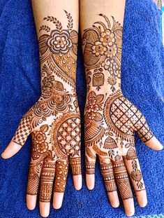 two hands with henna tattoos on them, one is showing off the intricate design