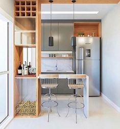 a kitchen with two stools and a table in the center, next to a refrigerator