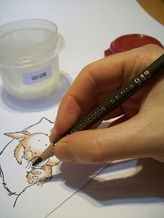 a person is holding a pencil and writing on a piece of paper with an animal drawn on it