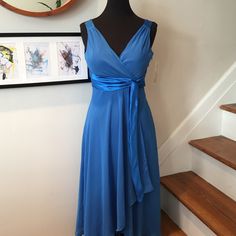 a blue dress is on display in front of a wall with pictures and a mirror