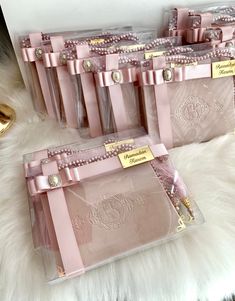 four pink bags with pearls and bows on them sitting on a white fur covered floor