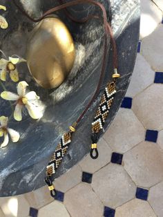 a black and white beaded necklace sitting on top of a table next to flowers