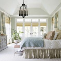 a bedroom with a bed, dresser and chandelier