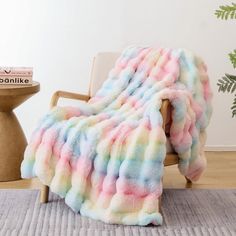 a multicolored blanket sitting on top of a chair next to a potted plant