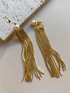 PEARL DANGLE TASSEL EARRINGS WITH SILVER PIN Dangling with your movement, these gold tassel pearl earrings create an elegant and delicate look. The dangling pearl earrings consist of an 6-7mm real pearl and 6cm length gold tassels. The pin is made of sterling silver to keep your skin safe and comfortable. PRODUCT SPECIFICATIONS Pearl type Freshwater Pearl shape Near round Pearl size 6-7mm Pearl color White Pearl quality AAA Stock number 7094 Metal S925 silver pins; 14k gold plated alloy tassel F Pearl Earring Jacket, Real Pearl Earrings, Earring Jackets, Freshwater Pearls Earrings, Silver Pin, Real Pearls, Pearl Types, Pearl Earrings Dangle, Pearl Color