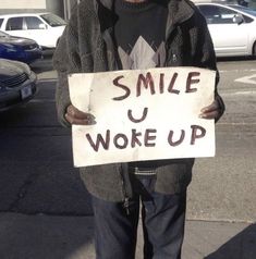 a man holding a sign that says smile u woke up