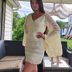 a woman in a crocheted dress standing on a porch