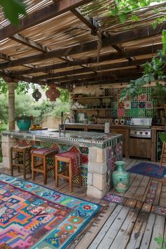 an outdoor kitchen with colorful rugs on the floor and wooden tables in the middle