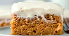 a piece of carrot cake on a plate with a fork and milk jug in the background