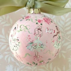 a pink ornament with a green bow hanging from it's side on a wall