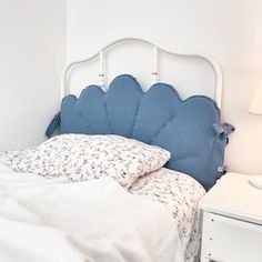 a white bed with blue headboard in a bedroom next to a night stand and lamp