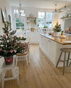 a christmas tree is in the center of a kitchen with white cabinets and countertops