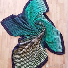 a green and black scarf laying on top of a wooden floor