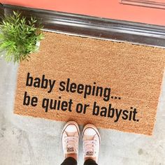 a person standing in front of a door mat that says baby sleeping be quiet or babysitt