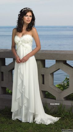 a woman in a white dress is standing by the water with her hands on her hips