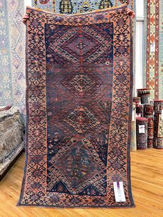 an antique rug is on display in a room with wooden floors and wall hangings