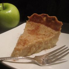 a piece of pie sitting on top of a white plate next to an green apple