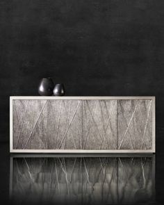 two black vases sitting on top of a wooden shelf next to each other in front of a dark wall