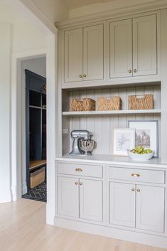 a kitchen with white cabinets and wooden floors