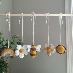 four crocheted flowers hanging from a clothes line with white and yellow pins attached to them