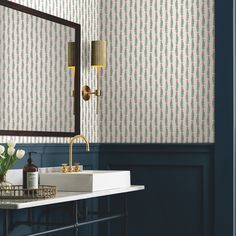 a bathroom with blue and white wallpaper, gold faucet, sink and mirror