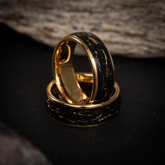 two gold rings with black and white designs on them sitting in front of a rock