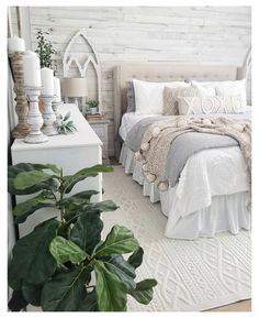 a bedroom with white bedding and green plants on the nightstands next to it