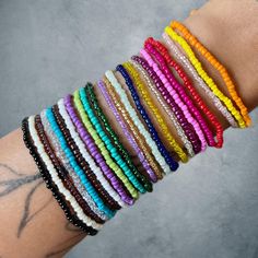 a person's arm with several different colored bracelets on top of each other