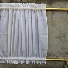 a curtain hanging on a wall next to a gold frame with grass growing in front of it