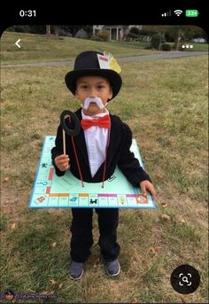 a young boy in a tuxedo and top hat holding an electronic board game