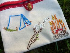 a handbag with embroidered designs on it sitting in the grass next to a fire