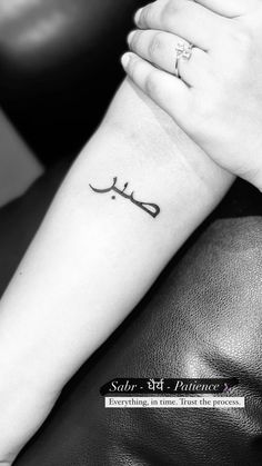 a black and white photo of a woman's arm with a tattoo on it