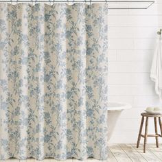 a shower curtain with blue flowers on it in a white bathroom next to a bathtub