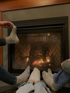 two people sitting in front of a fireplace with their feet up on the fire place