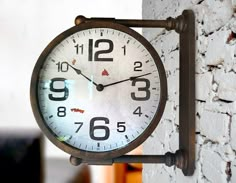 a clock is hanging on the side of a brick wall in front of a window