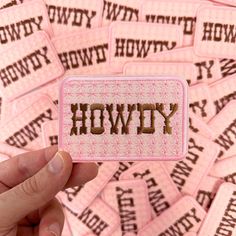 a person holding up a pink patch with the word hovvy written on it