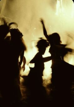 silhouettes of people dancing in front of a fire