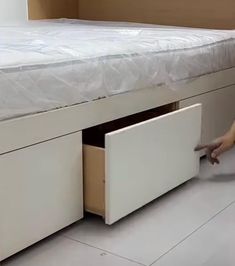 a person is reaching into a bed with two drawers