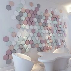 two white chairs sitting next to each other in front of a wall with hexagonal tiles on it