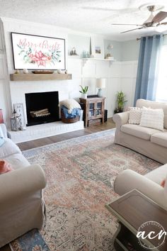 a living room with two couches and a rug in front of a fire place