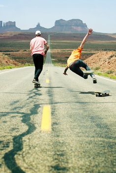 two skateboarders are doing tricks on the road