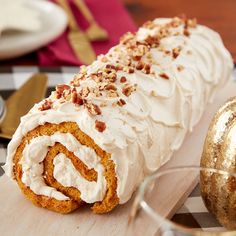 there is a large roll with white frosting and nuts on it next to a gold ornament