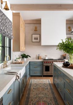 a kitchen with blue cabinets and an area rug in front of the stove top oven