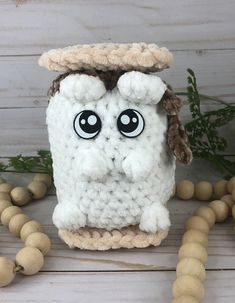 a crocheted white object with eyes and a hat on it's head